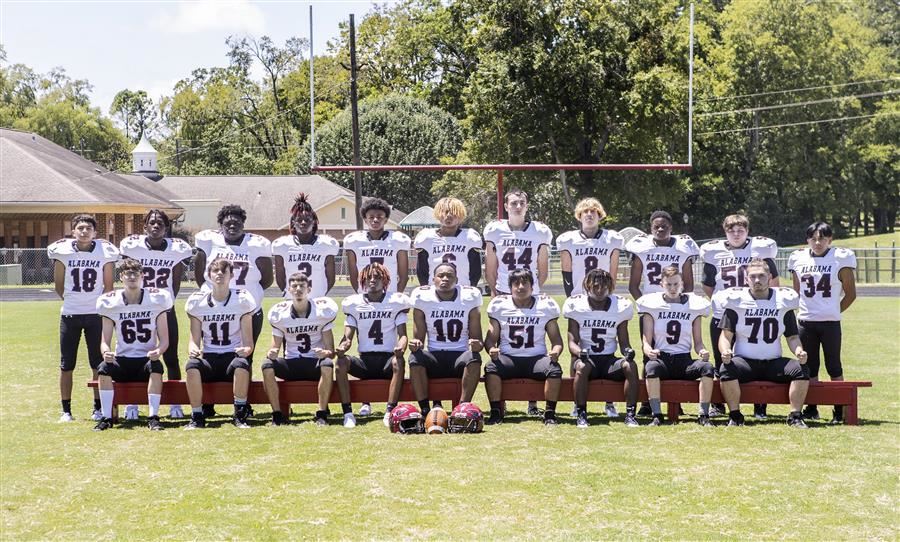 ASD's football team looks to camera. The first row sits on a bench while a second row stands behind.